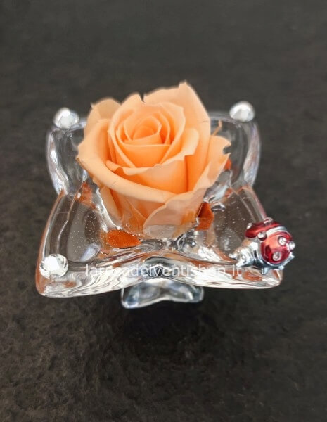 Calice in vetro con rosa stabilizzata e coccinella